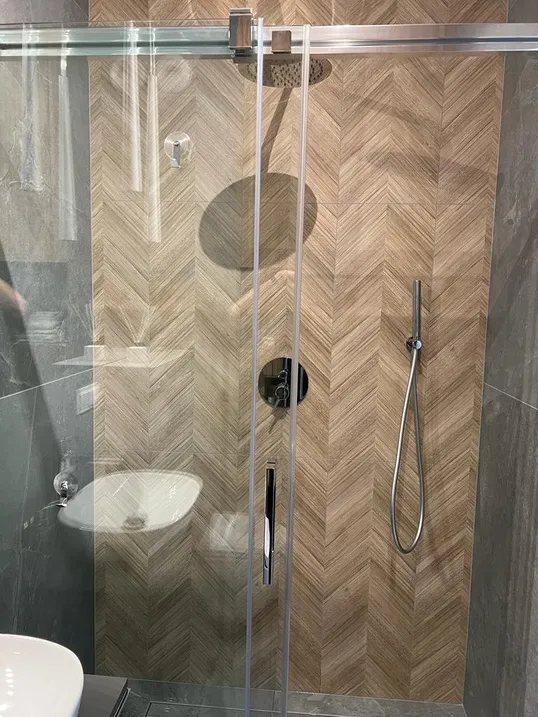 Prysznic walk-in ze szklaną taflą, deszczownicą i płytkami ułożonymi w jodełkę